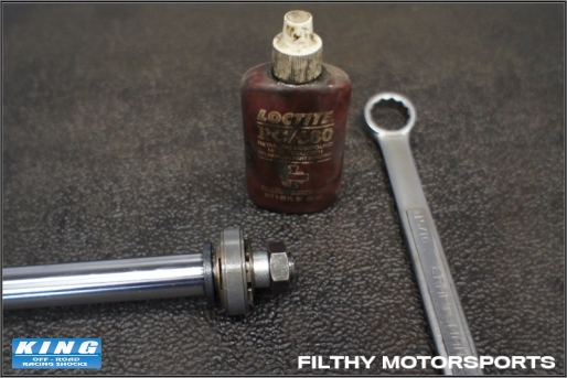 A photo of a bottle of loctite and a wrench next to the shaft assembly piston nut