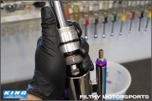 A photo of a King shock shaft assembly removed from the shock cylinder held by a hand wearing a black glove